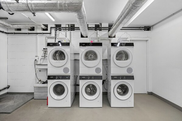 A laundry facility with multiple Siemens branded washing machines, ventilation ducts, and a tiled floor. - Westside Penthouse with a sauna, fireplace, balcony, and underground parking space (Sylt)