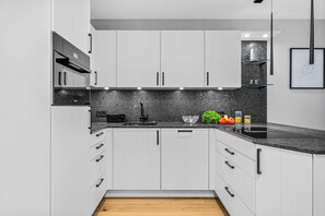 Eine moderne Küche mit weißen Schränken, einer Granit Arbeitsplatte und Holzboden.