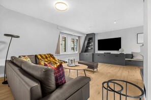 Ein modernes Wohnzimmer mit einer Couch, einem Couchtisch und einem Flachbildfernseher.