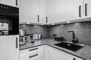 Eine moderne Küche mit weißen Schränken, einer Granitabdeckung, einem eingebauten Toaster und einem schwarzen Spülbecken.