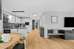 A modern kitchen with white cabinets, a wooden dining table, and a bench. - Eastside Penthouse with a sauna, fireplace, balcony, and underground parking space (Sylt)