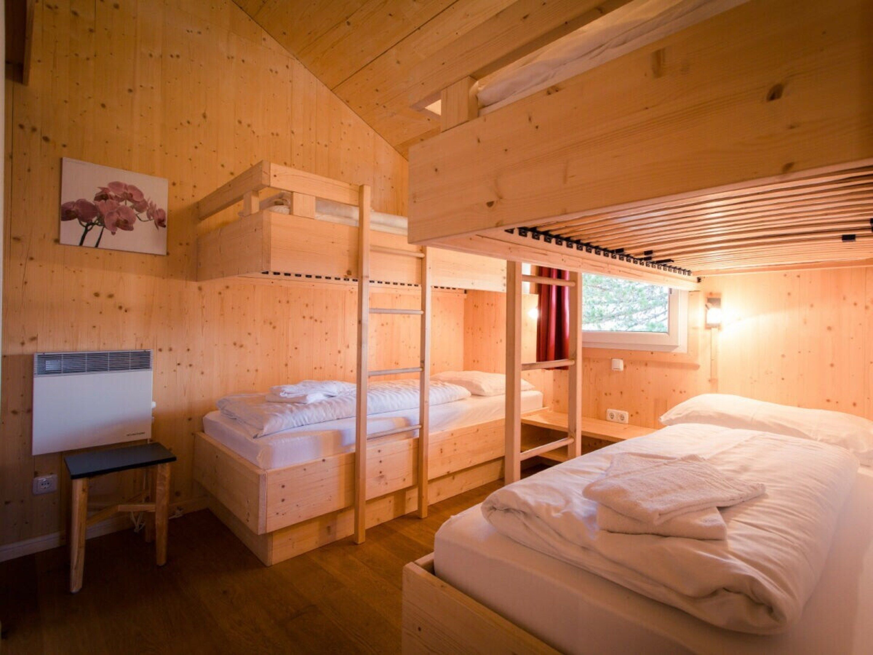 Une cabane en bois avec des lits superposés, un bureau et une fenêtre avec des rideaux.