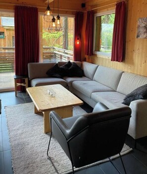 A cozy living room with a sofa, a coffee table, and a black chair. - Cabin in Turrach With Sauna and Balcony (Stadl-Predlitz)