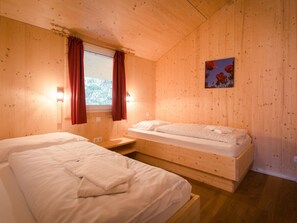 A wooden room with two beds, a window with curtains, and a painting on the wall. - Cabin in Turrach With Sauna and Balcony (Stadl-Predlitz)