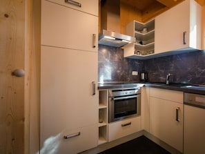 A modern kitchen with built-in appliances, wooden cabinets, and a marble backsplash. - Cabin in Turrach With Sauna and Balcony (Stadl-Predlitz)