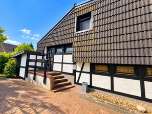 A traditional building with a steeply pitched roof, a small window, and a brick staircase leading to the entrance. - Experience pure relaxation at the family-friendly KÜSTENKIND vacation home in Burhav (Burhave)