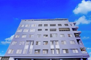 Un edificio de varios pisos con fachada plana y numerosas ventanas, algunas con rejas de metal.