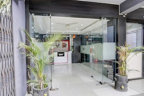 Un lobby moderno de hotel con puertas de vidrio, plantas en macetas y un mostrador de recepción.