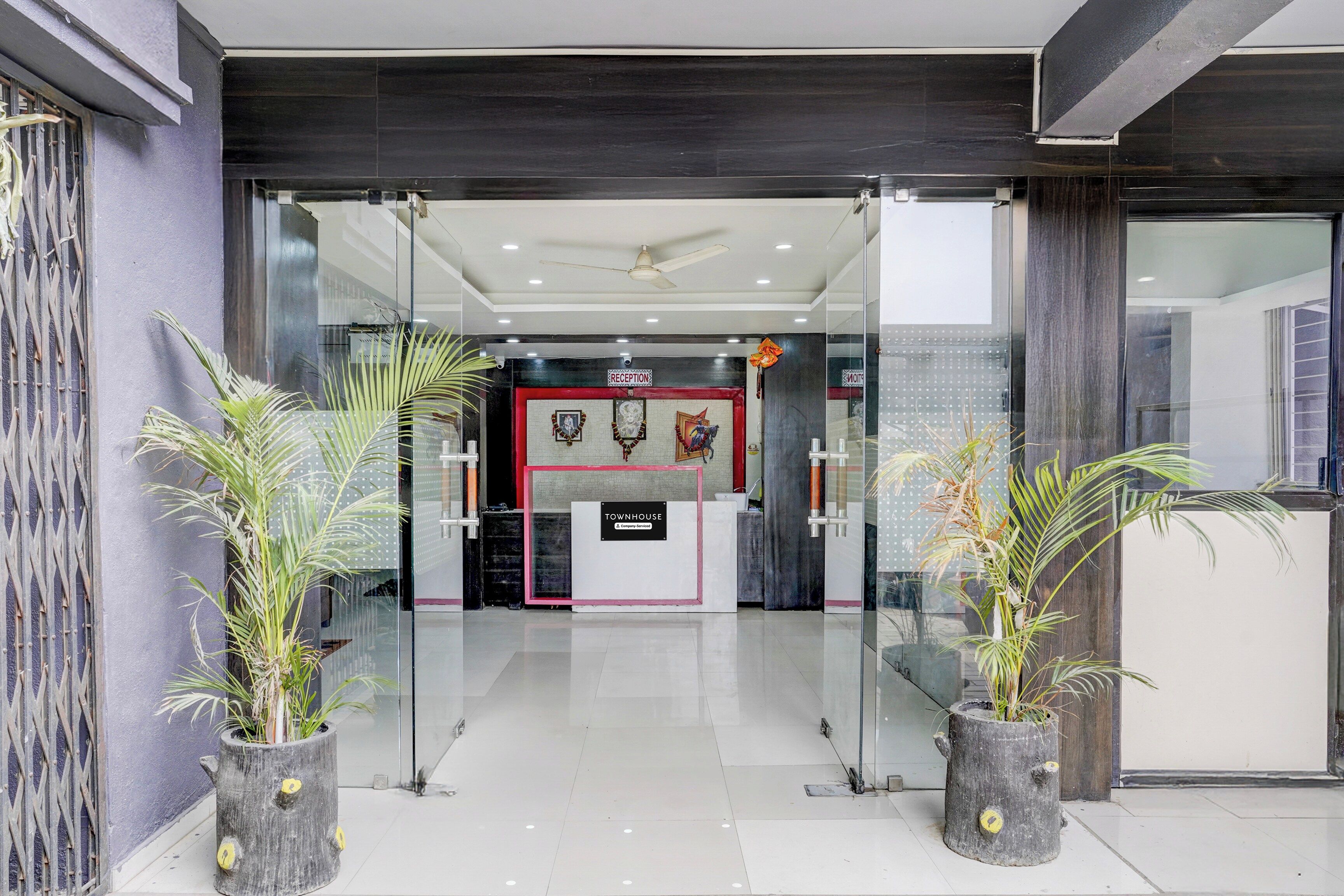Un área de recepción con puerta de vidrio, mostrador de recepción y un cartel que indica 'RECEPTION'.