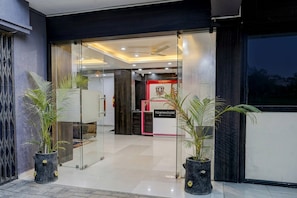 Una entrada de hotel moderna con puertas de vidrio, plantas en macetas y un letrero que dice 'TOWNHOUSE'.