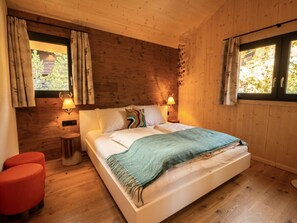 A wooden-paneled bedroom with a bed, two bedside lamps, and a window with curtains. - Superior Chalet # 56 With Sauna & Hot Tub (Stadl-Predlitz)