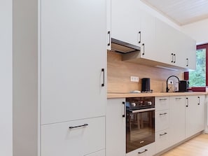 Eine moderne Küche mit weißen Schränken, einem Backofen und einer Kaffeemaschine.