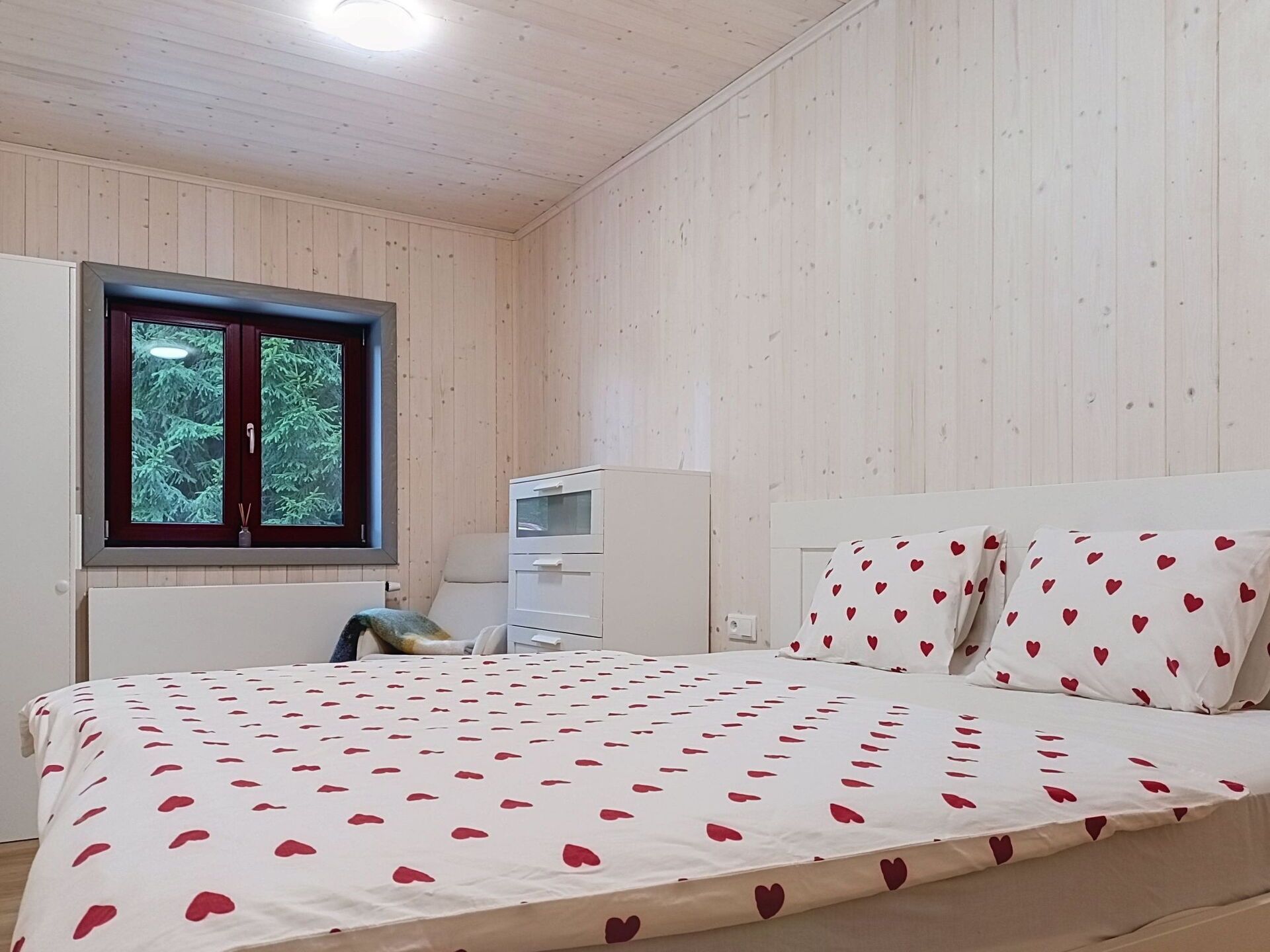 Une chambre à coucher avec un lit, une commode, une fenêtre et une armoire.