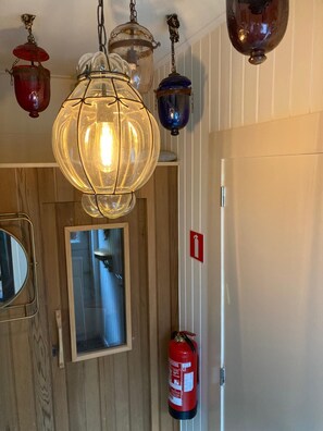 A room with a wooden door, a mirror, a fire extinguisher, and a hanging light fixture. - Apartment for 4 people with a private sauna by the water, breakfast service, and parking (Bruinisse)