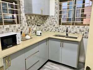 A kitchen with a microwave, toaster, and sink. - Contemporary City Flat with Comfortable Bedroom & Spacious Living Area (Accra)