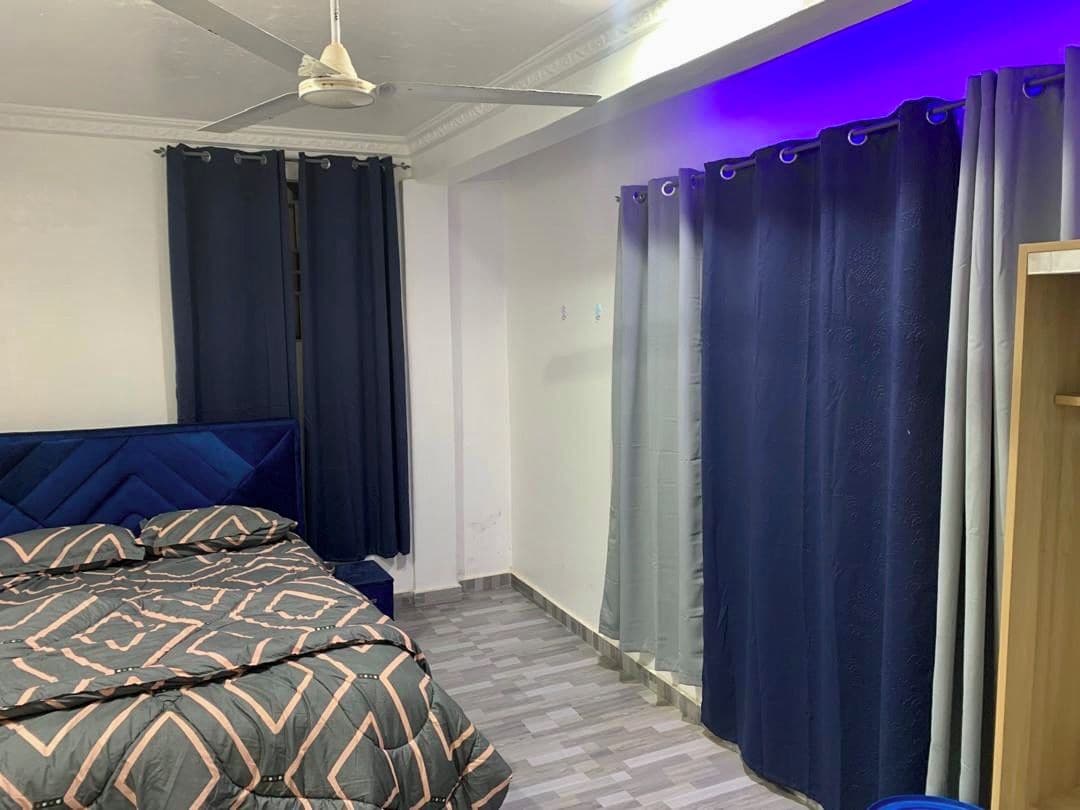 Et soveværelse med seng, ventilator og gardiner.