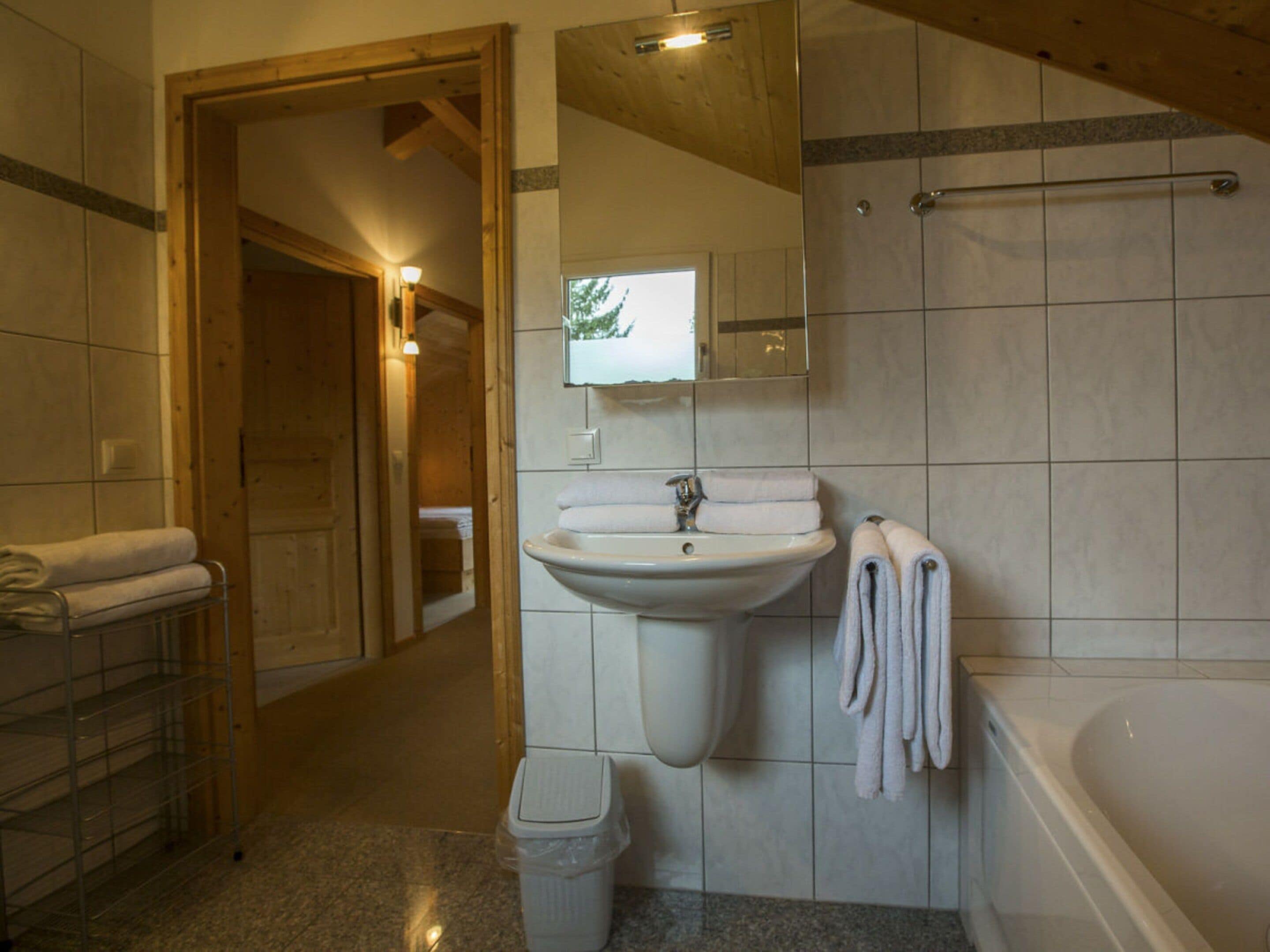 A bathroom with a sink, mirror, and bathtub.