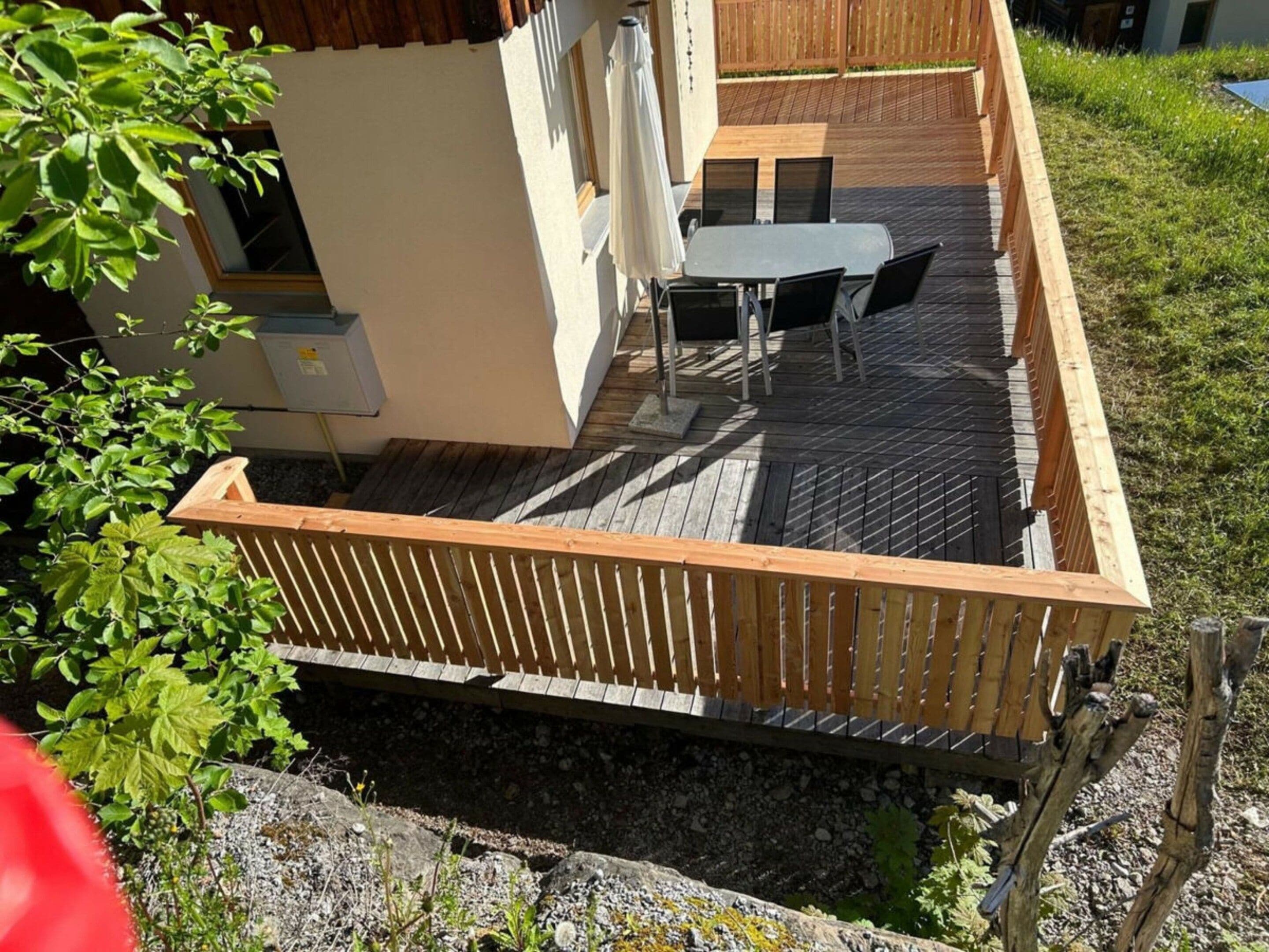 Una terraza de madera con una mesa y sillas, rodeada por una valla de madera.