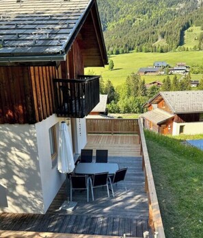 A wooden cabin with a deck, outdoor seating, and a view of a green valley. - Cabin in Annaberg With Swimming Pool (Annaberg-Lungoetz)