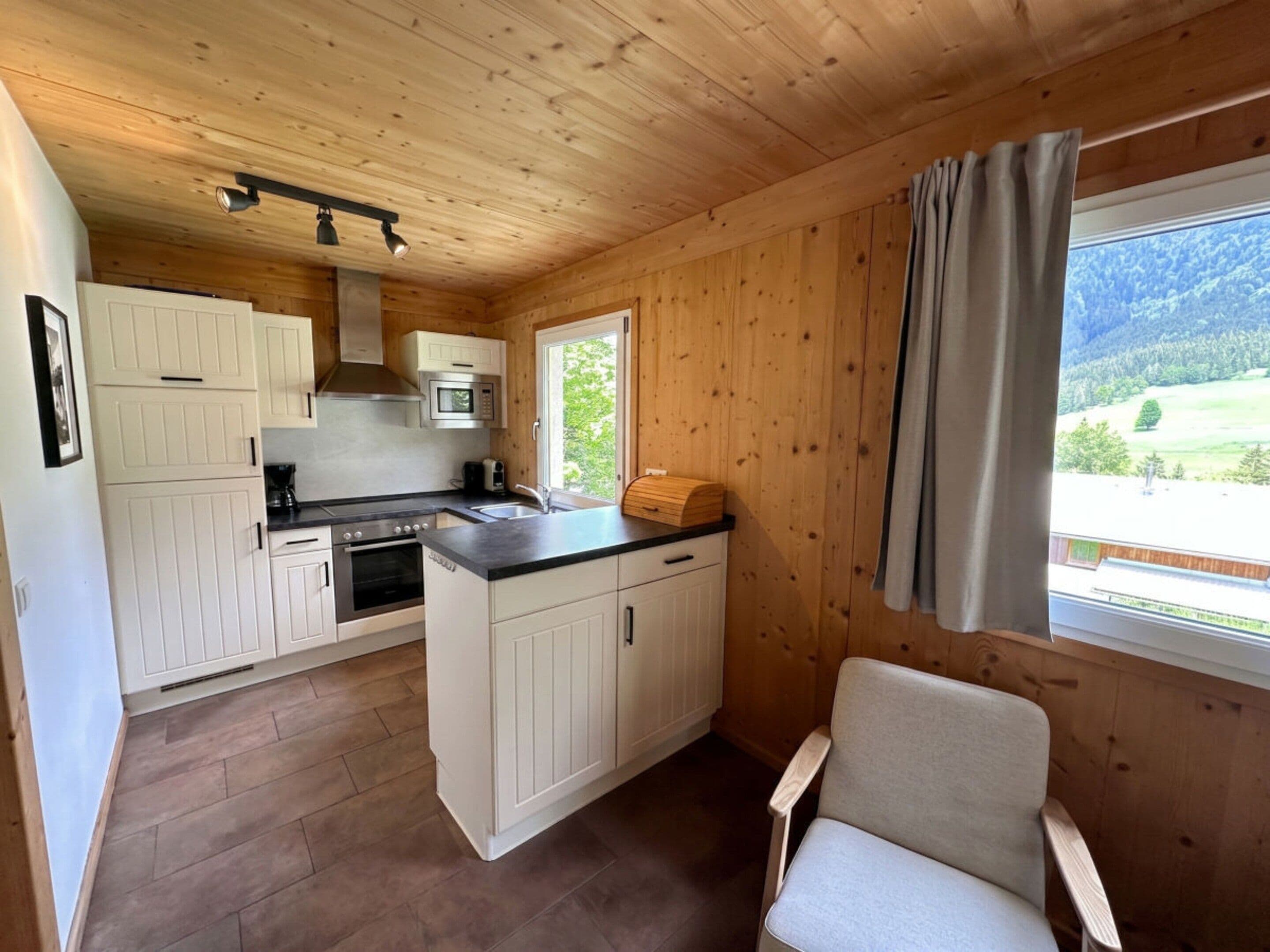 Eine kleine Küche mit Holzwänden und Blick auf eine grüne Landschaft.