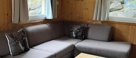 Una habitación acogedora con un sofá modular, una mesita con una planta y vasos, y un ventilador de techo.