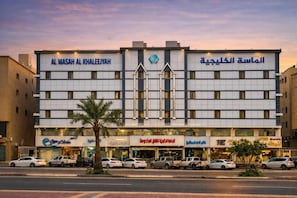 A hotel with multiple floors, a prominent sign in Arabic, and several storefronts on the ground level.