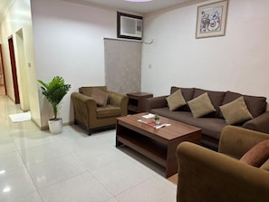 A living room with two sofas, a coffee table, and a potted plant.