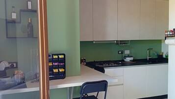 A compact kitchen with a dining area, a small table, and a chair.