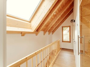 A wooden interior with a sloped ceiling, a wooden staircase, and a door. - Chalet #1 With 2 Bedrooms and Sauna (Oberwölz)