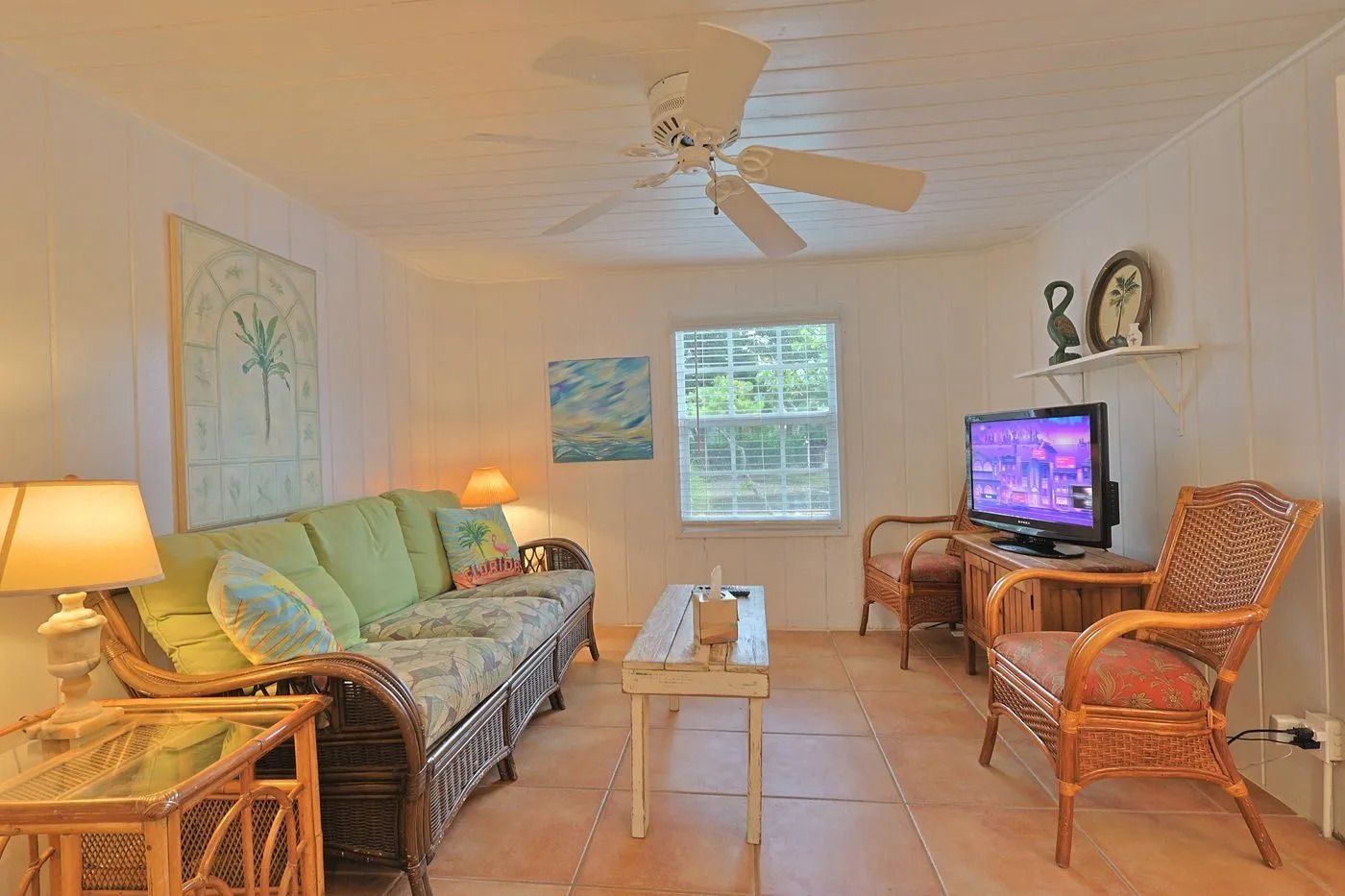 A living room with a sofa, chairs, a television, and a ceiling fan.