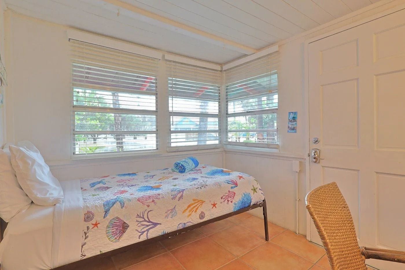 A room with a bed, a chair, and a door.