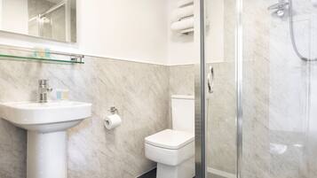 Un baño moderno con cabina de ducha de vidrio, un lavabo blanco y un inodoro.