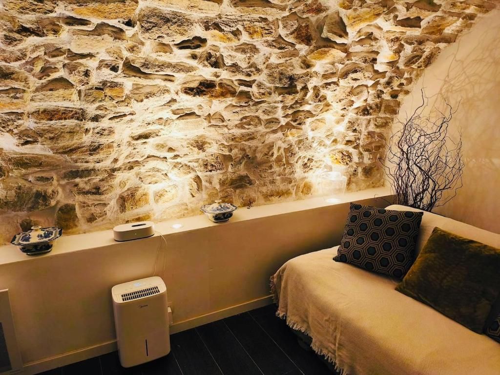 A room with a stone wall, a sofa, a small table, and a decorative branch.