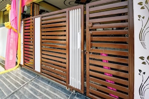 A set of brown metal gates with vertical slats and a white vertical panel in the center.