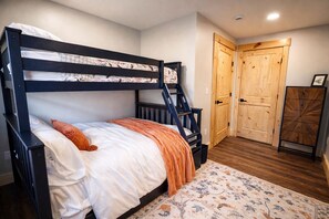 A bunk bed with a wooden ladder, a white mattress, and an orange throw pillow. - Luxury Mountain Escape • 6BR • Hot Tub & Views • 4mi to Sunday River (Bethel)