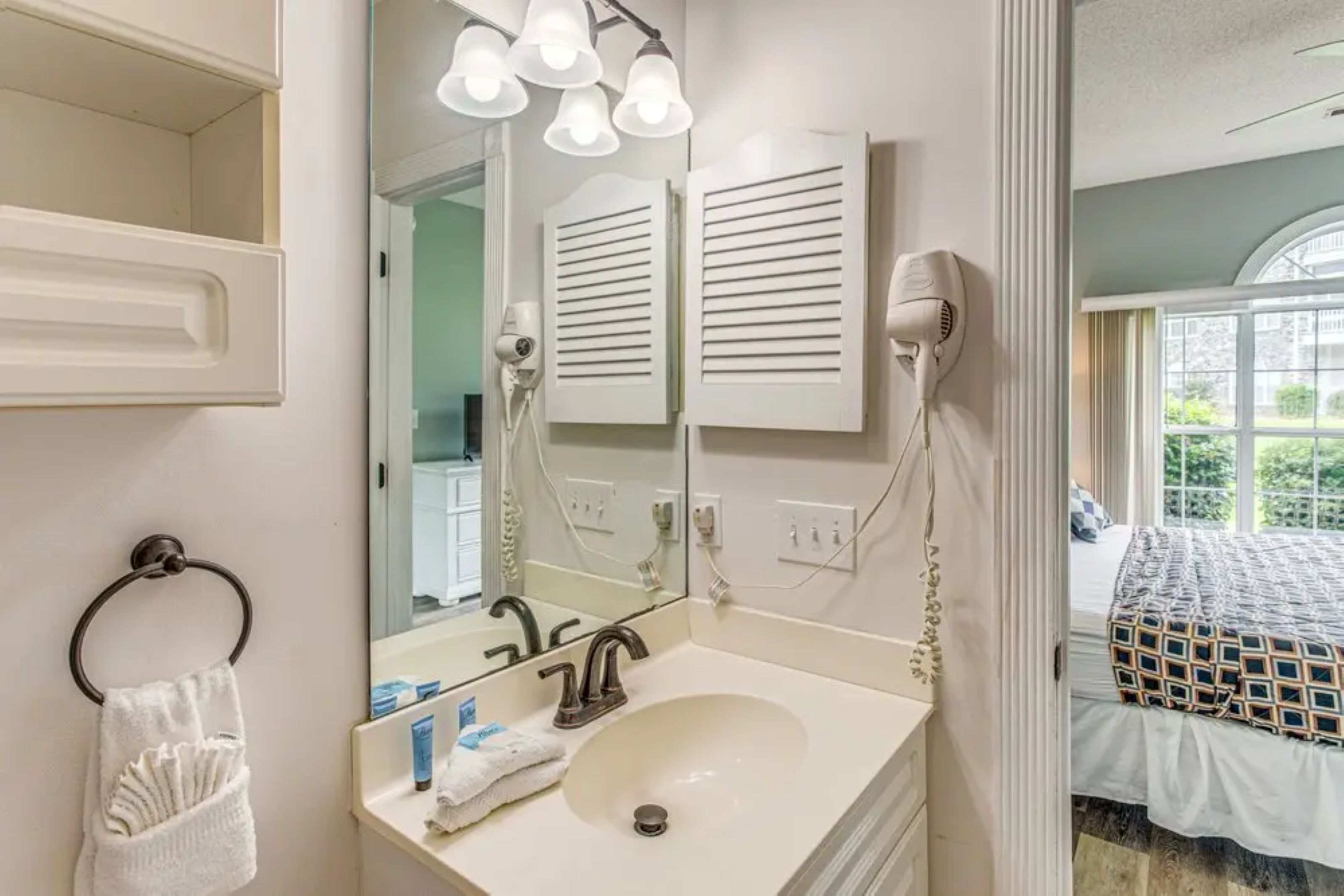 A bathroom with a sink, mirror, towel rack, and a hairdryer on the wall.