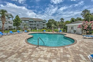 A swimming pool with a brick deck, surrounded by lounge chairs and a multi-story building in the background. - Myrtlewood Fall Special | Ground-Floor 2BR, Steps to Golf, Minutes to Beach (Myrtle Beach)