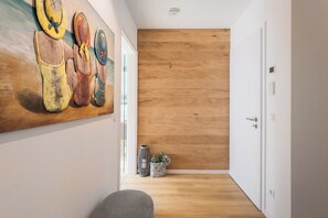 Ein Flur mit Holzboden, einem Gemälde an der Wand und einer Tür am Ende.