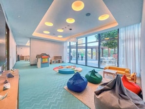 Ein Kinderspielbereich mit bunten Sitzsäcken und einer weichen Krabbeldecke.