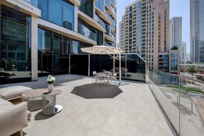 Eine Dachterrasse mit Gartenmöbeln, einer Glasbrüstung und Blick auf umliegende Hochhäuser.