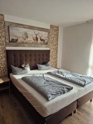 A bedroom with a large bed, two pillows, a headboard, and a wall-mounted artwork of deer.