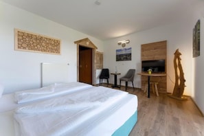 Habitación de hotel con cama, escritorio, silla, televisor y un panel de pared de madera.