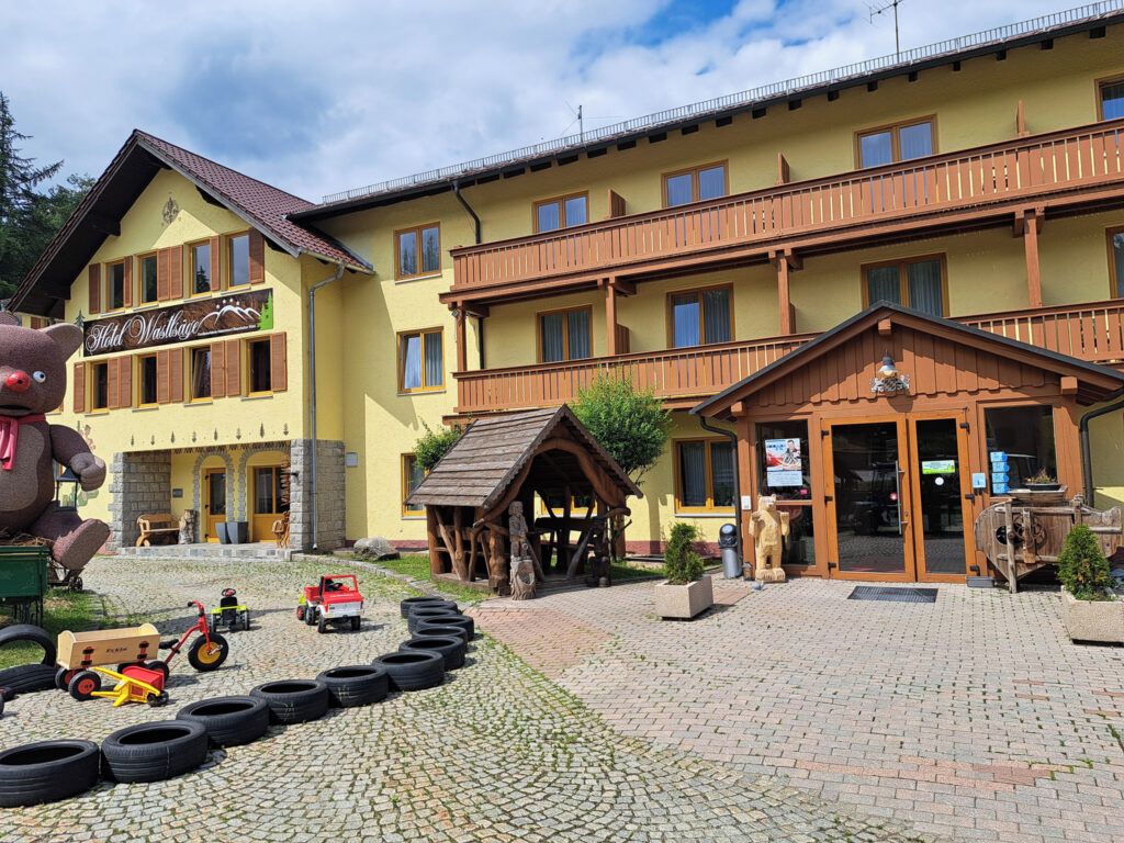 Ein Hotel mit gelber Fassade, Holzbalkonen und einem Eingangsbereich mit einem Schild.