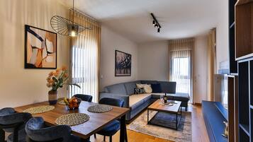A modern living room with a wooden dining table, blue sofas, and a coffee table.