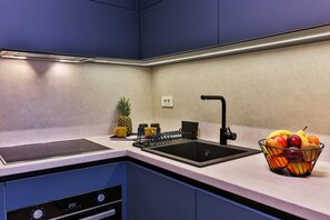 Una cocina moderna con lavavajillas integrado, un lavamanos con grifo negro y un frutero en la encimera.