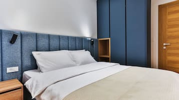 Un dormitorio con una cama, una mesita de noche, un armario de madera y una estantería de pared.