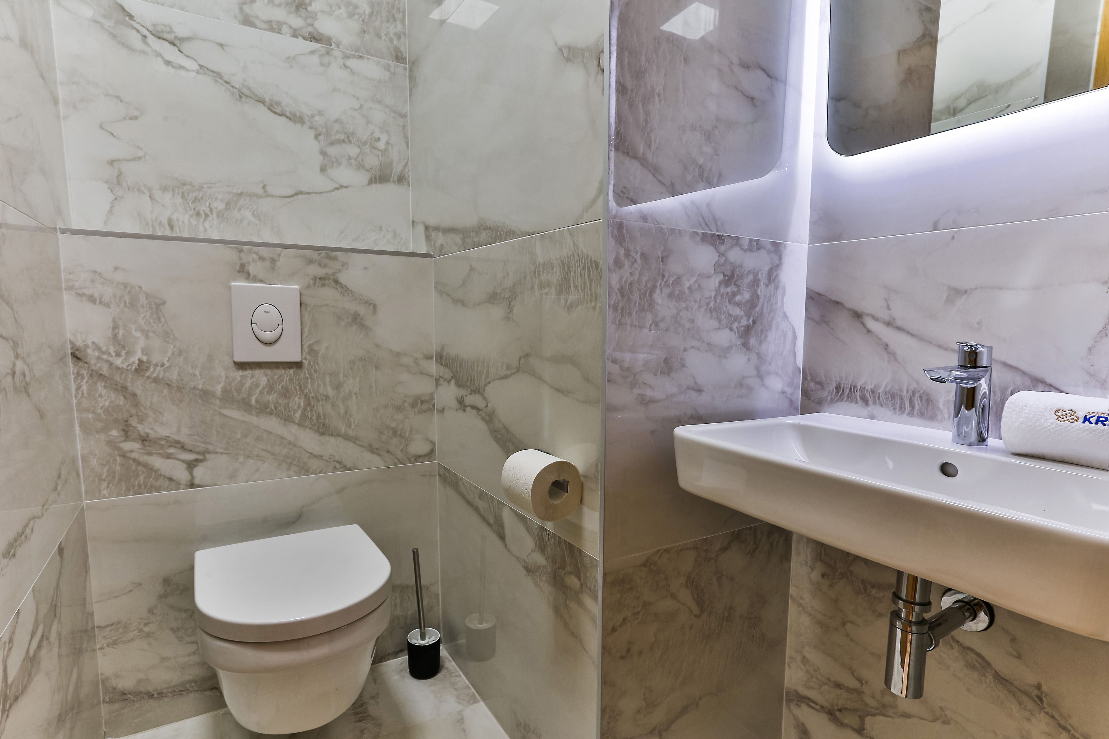 Ein Badezimmer mit Toilette, einem Handtrockner und einem Waschbecken mit Spiegel darüber.