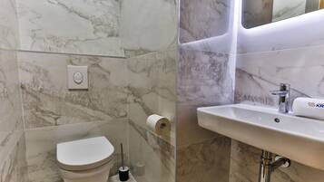 Ein Badezimmer mit Toilette, einem Handtrockner und einem Waschbecken mit Spiegel darüber.