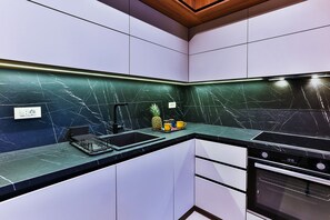 Una cocina moderna con una paleta de colores blanco y negro, horno empotrado y pileta de acero inoxidable.
