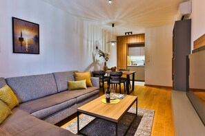 En moderne stue med sofa, sofabord og et spiseområde med stole.